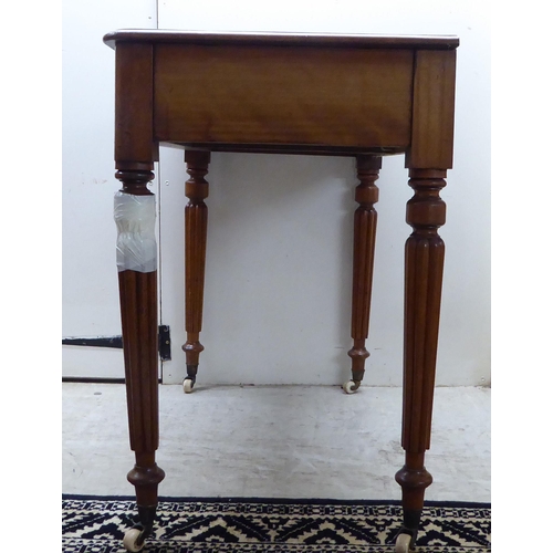 48 - A mid Victorian mahogany writing table with two side drawers, raised on reeded, tapered legs and cas... 