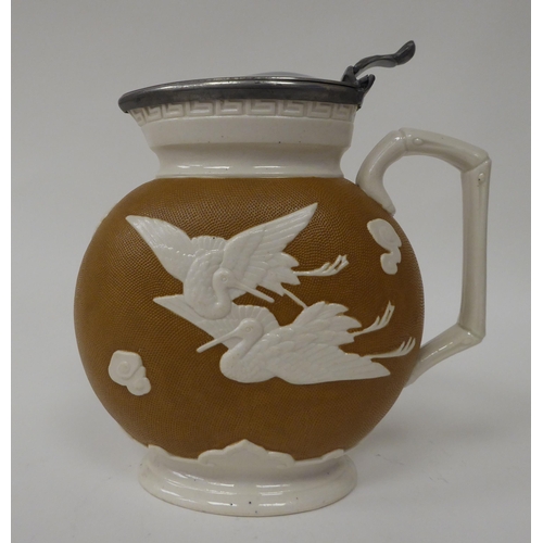 49 - A late Victorian cream and textured glazed china jug of flattened, oval form, decorated with cranes ... 