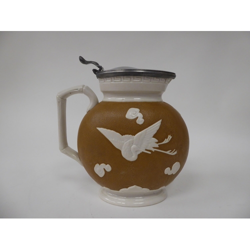 49 - A late Victorian cream and textured glazed china jug of flattened, oval form, decorated with cranes ... 