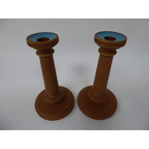 56 - A pair of late 19th/early 20thC Watcombe Torquay terracotta candlesticks with blue glazed sconces an... 