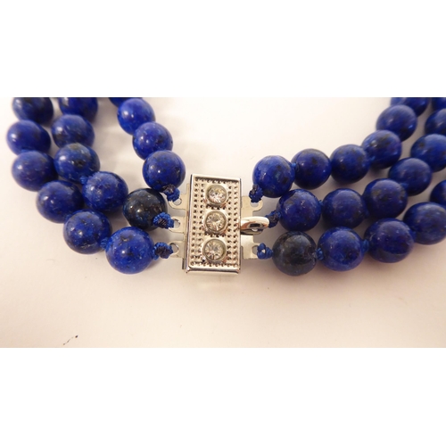 65 - A modern lapis lazuli coloured suite of jewellery, viz. a triple row necklace, a bracelet, ring and ... 