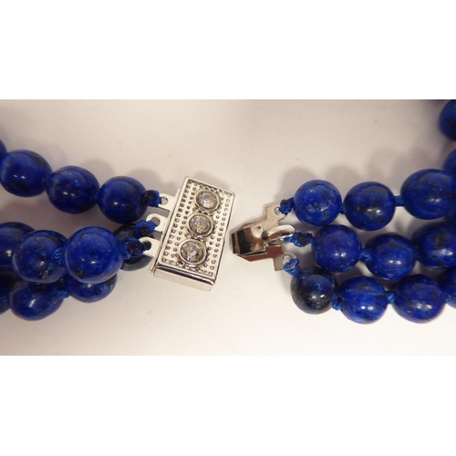 65 - A modern lapis lazuli coloured suite of jewellery, viz. a triple row necklace, a bracelet, ring and ... 