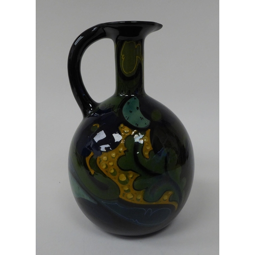 69 - A Gouda china spherical spirits bottle with a narrow neck, strap handle and pouring lip, decorated i... 