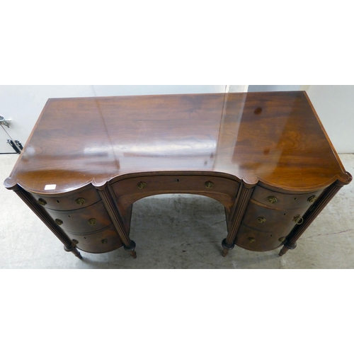 76 - An Edwardian string inlaid mahogany, one piece breakfront kneehole sideboard with an arrangement of ... 