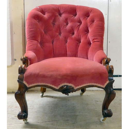 87 - A late Victorian walnut framed and red fabric upholstered nursing chair, raised on carved cabriole l... 