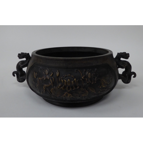 88 - A 19thC Chinese bronze censer with twin heraldic iron handles, decorated with floral vignettes  bear... 