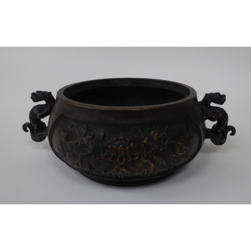 88 - A 19thC Chinese bronze censer with twin heraldic iron handles, decorated with floral vignettes  bear... 