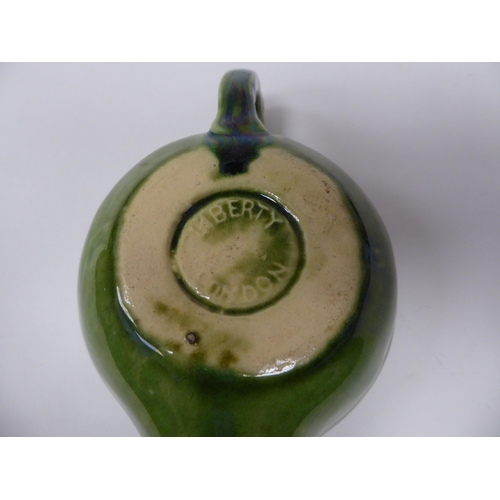 99 - A Liberty of London green glazed and scroll decorated stoneware oil lamp base with a carrying handle... 