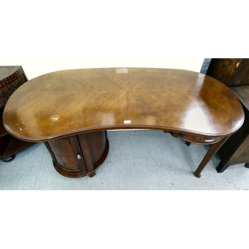 398 - A modern mahogany finished kidney shaped desk with twin pedestal, one with a drawer, the other, a dr... 