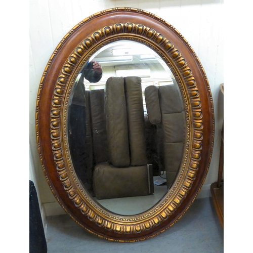 409 - A modern mirror, the oval plate in a gilded composition frame  47