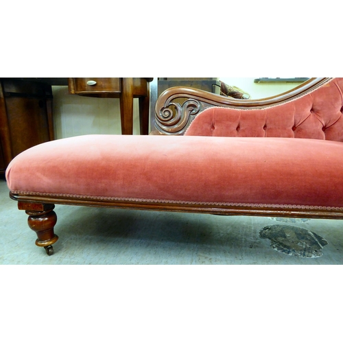 62 - A late Victorian mahogany framed chaise lounge, upholstered in a maroon coloured fabric, raised on t... 