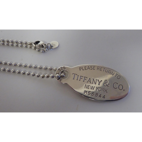 286 - A Tiffany & Co silver dog tag pendant with engraved decoration, on a ring link neckchain