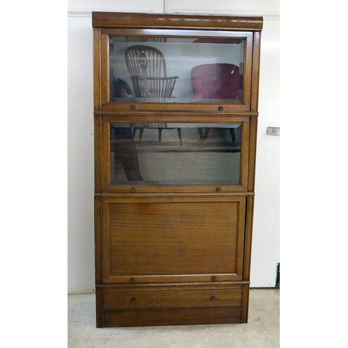 295 - A 1930s mahogany three section stacking bookcase with lift and slide doors, on a plinth incorporatin... 