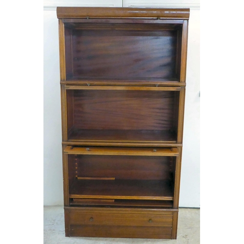 295 - A 1930s mahogany three section stacking bookcase with lift and slide doors, on a plinth incorporatin... 