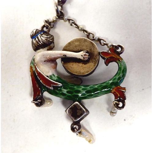 382 - An early 20thC probably white metal and coloured enamel novelty mermaid pendant with an unmatched bo... 