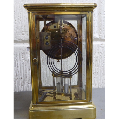 401 - An early 20thC brass and glazed mantel clock; the mercury weighted movement faced by an Arabic dial&... 