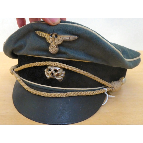 73 - A German SS green and black peaked cap with white piping, emblems and a cord(Please Note: this lot i... 