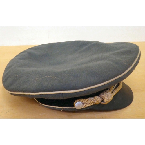 73 - A German SS green and black peaked cap with white piping, emblems and a cord(Please Note: this lot i... 