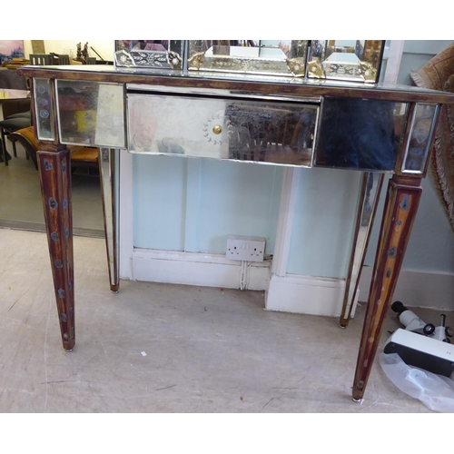 83 - A modern Venetian style partially mirrored dressing table with a central drawer, raised on square, t... 