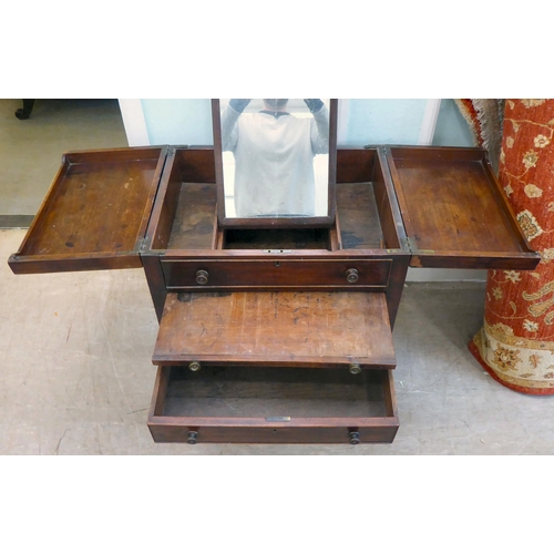 87 - A George III mahogany vanity unit with a pair of hinged flaps, revealing a mirror, over a brushing s... 