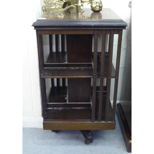 90 - An early 20thC mahogany two tier, open front revolving bookcase, on a splayed plinth and casters&nbs... 