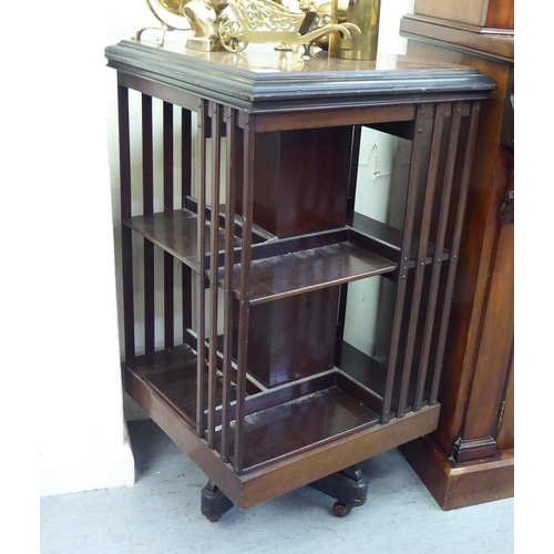 90 - An early 20thC mahogany two tier, open front revolving bookcase, on a splayed plinth and casters&nbs... 