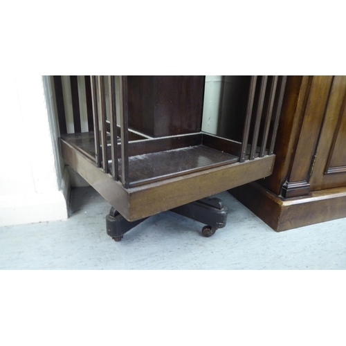 90 - An early 20thC mahogany two tier, open front revolving bookcase, on a splayed plinth and casters&nbs... 