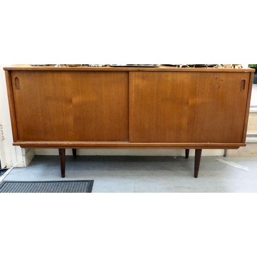 92 - A 1970s teak sideboard with a pair of sliding doors, raised on turned, tapered legs  29