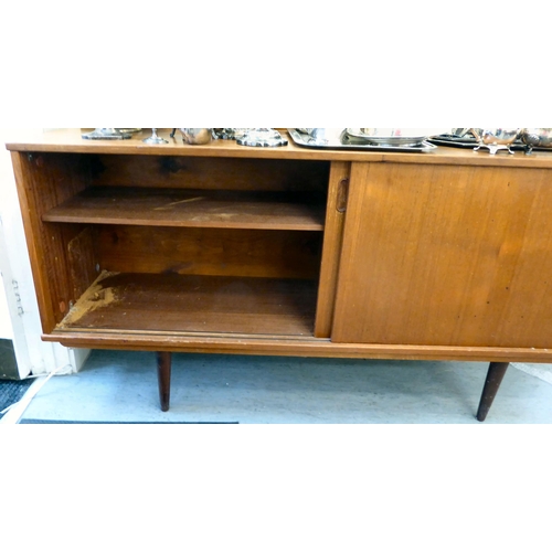 92 - A 1970s teak sideboard with a pair of sliding doors, raised on turned, tapered legs  29