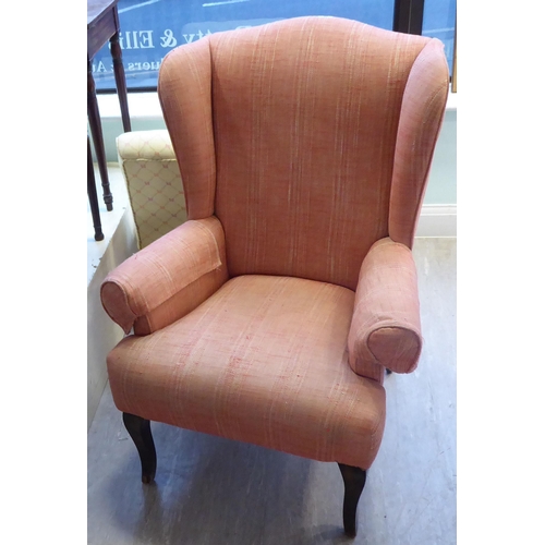 94 - A John Lewis wingback chair, upholstered in red fabric, raised on tapered forelegs