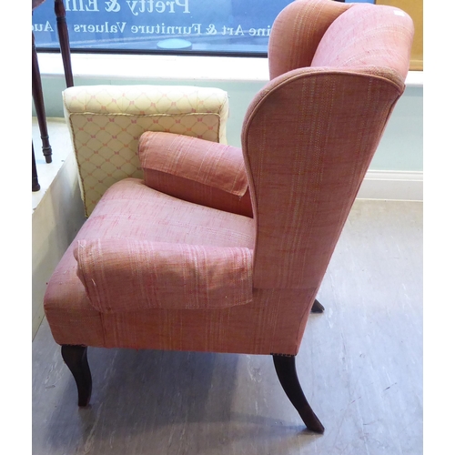 94 - A John Lewis wingback chair, upholstered in red fabric, raised on tapered forelegs