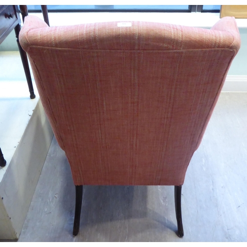 94 - A John Lewis wingback chair, upholstered in red fabric, raised on tapered forelegs