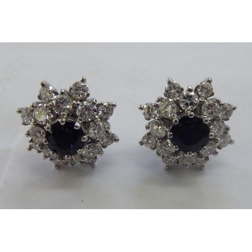 229 - A pair of 18ct white gold, sapphire and diamond cluster earrings