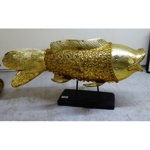 151 - A modern antique finished, gilt painted, carved wooden and amber coloured model carp, on stilts and ... 