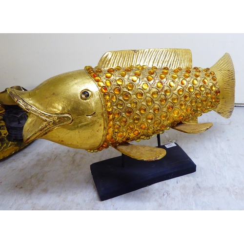 151 - A modern antique finished, gilt painted, carved wooden and amber coloured model carp, on stilts and ... 