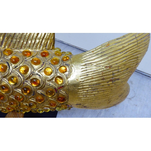 151 - A modern antique finished, gilt painted, carved wooden and amber coloured model carp, on stilts and ... 