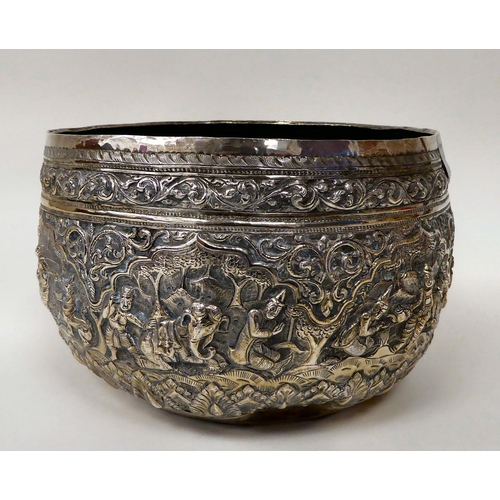 18 - An Asian white metal bowl, cast, embossed and chased with figures, wild animals, stiff leaf and othe... 