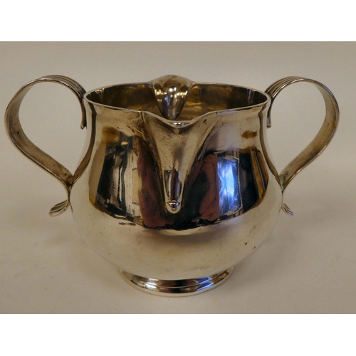 181 - An Edwardian silver cream jug of tapered, bulbous form with opposing pouring lips and twin S-shaped ... 