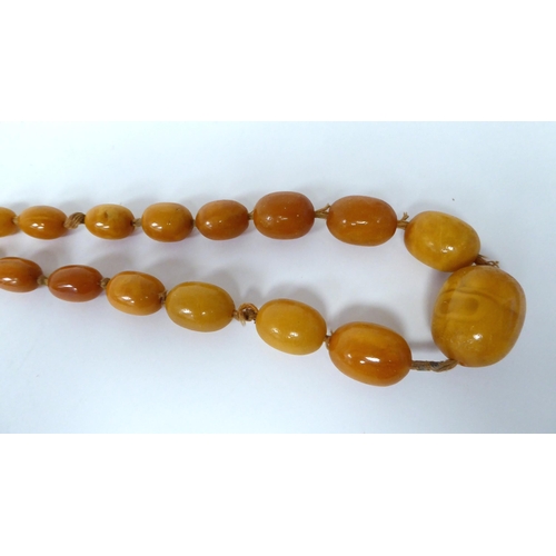 34 - A string of graduated, oval, amber coloured beads  30