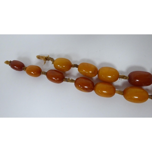 34 - A string of graduated, oval, amber coloured beads  30