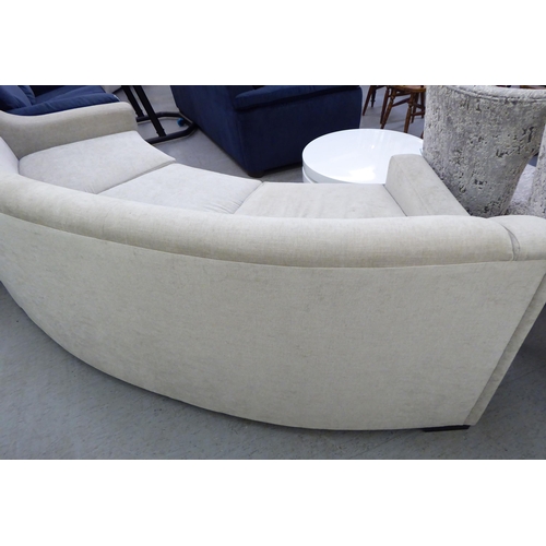 119 - A modern curved, three person settee, upholstered in a cream/Champagne coloured fabric  120