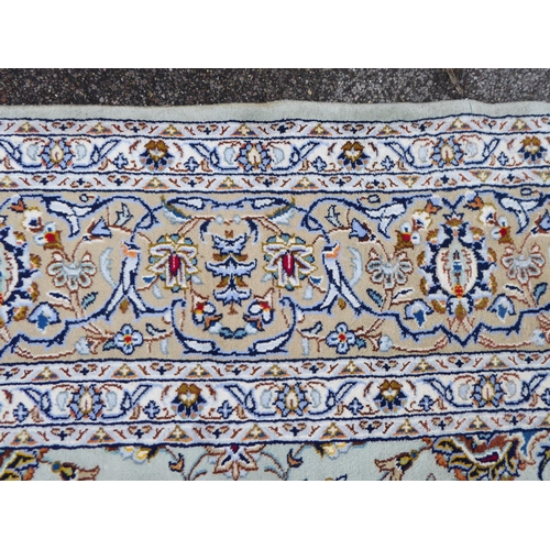 274 - A Persian Kashan design carpet, decorated with repeating floral and geometric patterns, on a pale bl... 