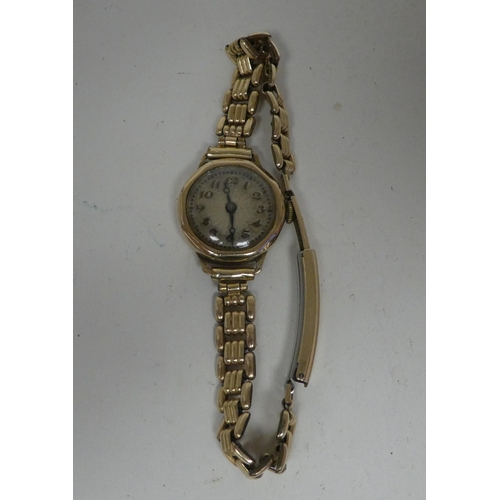 6 - A lady's 9ct gold cased wristwatch, faced by an Arabic dial, on a yellow metal strap