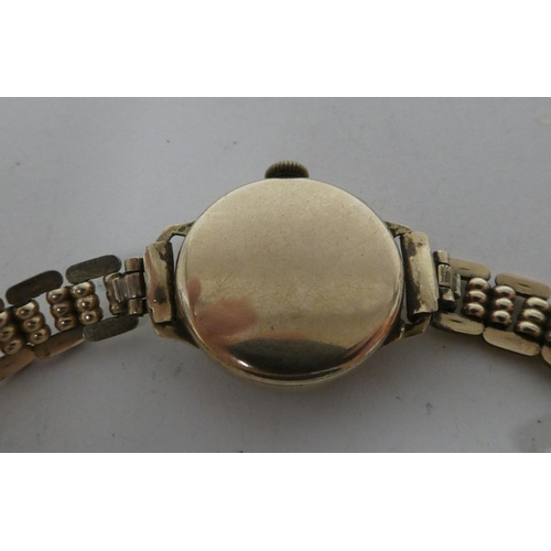 6 - A lady's 9ct gold cased wristwatch, faced by an Arabic dial, on a yellow metal strap