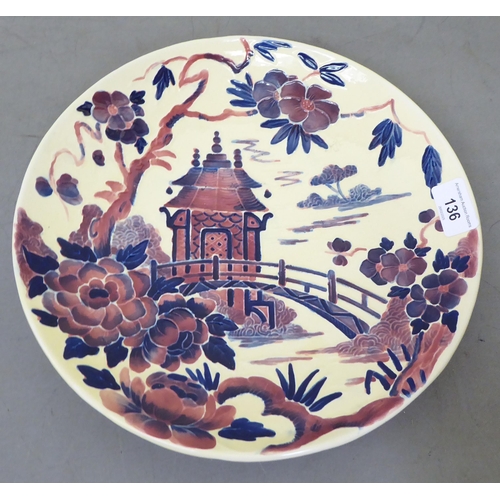 136 - A Crown Ducal Charlotte Rhead china wall plate, decorated in Oriental taste with a garden bridge and... 