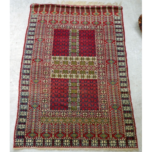 62 - An Afghan Ensi style rug, decorated with square panels and bordered by stylised designs, on a mainly... 