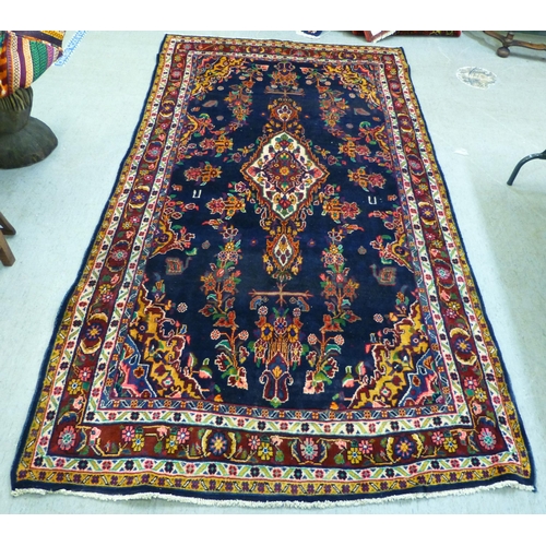 66 - A Hamadan design rug, decorated with floral motifs and a central medallion, on a navy blue ground&nb... 