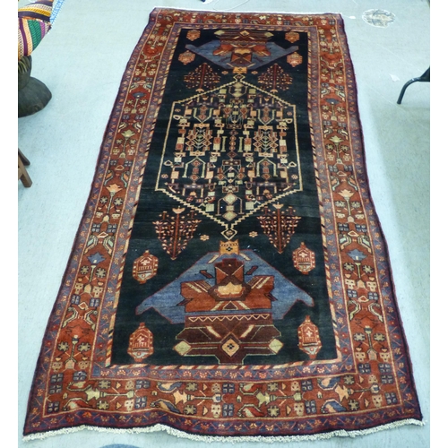 70 - A Hamadan design rug, decorated with geometric motifs and a central gul, on a black and red ground&n... 