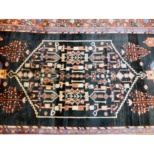 70 - A Hamadan design rug, decorated with geometric motifs and a central gul, on a black and red ground&n... 