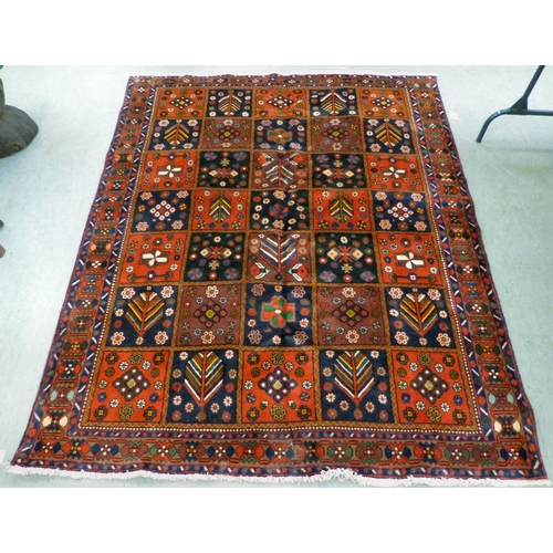 73 - A Bakhtiari design rug, decorated with a chequerboard of floral and geometric motifs, on a multi-col... 